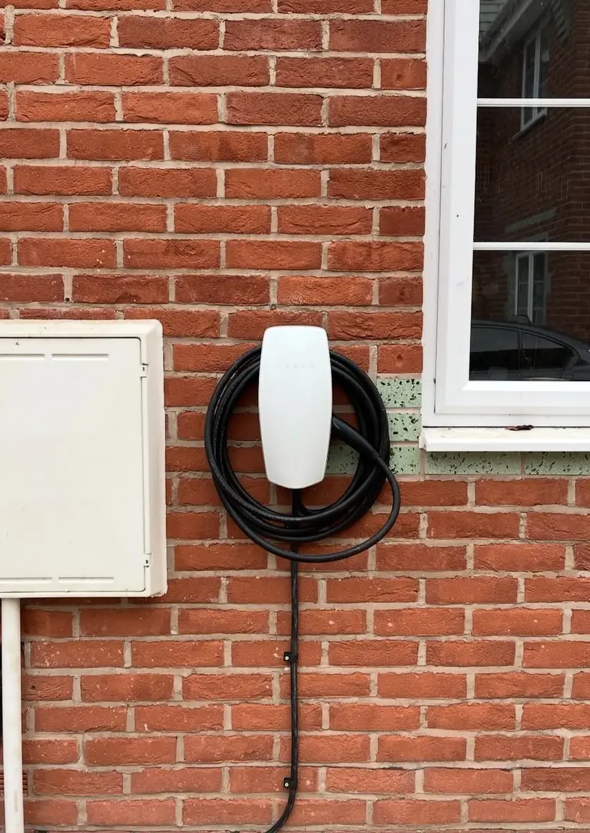 Tesla Wall Connector EV charger installed on a house wall